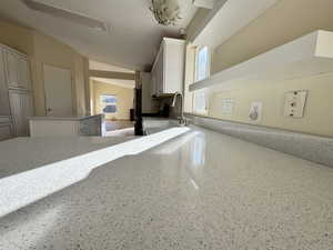 Kitchen view of white cabinets, a kitchen island, and light stone countertops