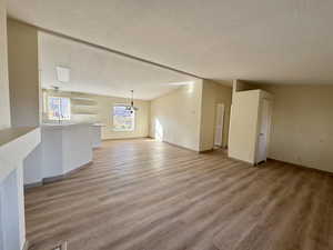 Living room featuring a textured ceiling, a chandelier, and light wood-type flooring