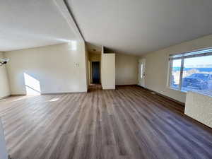 Living room featuring wood finished floors, a textured ceiling, and vaulted ceiling