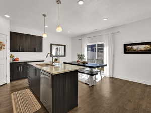 Kitchen with backsplash, light stone counters, hanging light fixtures, dark brown cabinets, and dark wood-style floors