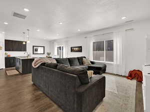 Living room featuring a textured ceiling, recessed lighting, and dark wood-type flooring