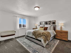 Primary Bedroom featuring a textured ceiling and dark colored carpet
