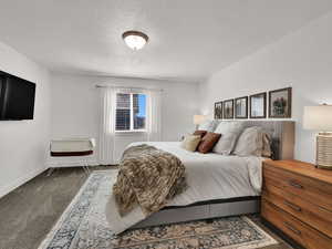 Carpeted bedroom featuring a textured ceiling and baseboards