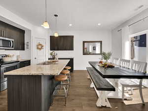 Kitchen with stainless steel appliances, dark brown cabinetry, tasteful backsplash, light stone counters, and recessed lighting