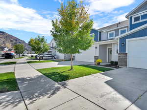 View of grassy yard with a residential view, concrete driveway, and a garage