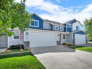 View of front of house featuring concrete driveway, a front yard, and an attached garage