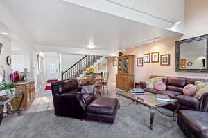 Living room featuring rail lighting, light tile patterned floors, stairway, and light colored carpet