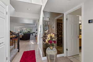 Hall featuring stairs and light tile patterned floors