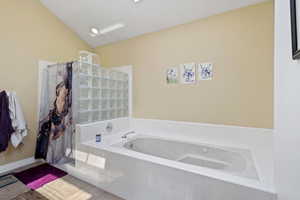 Bathroom featuring a garden tub, walk in shower, and tile patterned flooring