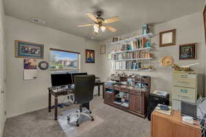 Home office with light colored carpet and a ceiling fan