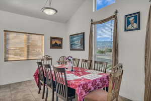 Dining space with lofted ceiling and light tile patterned flooring