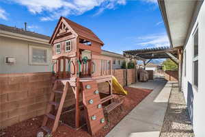 View of play area with a fenced backyard, a gate, and a pergola