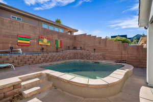 Outdoor pool with a hot tub and a patio