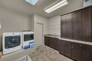 Laundry room featuring independent washer and dryer, a skylight, and cabinet space