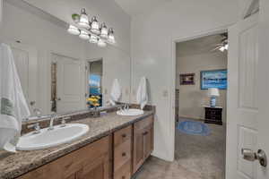 Bathroom featuring double vanity, light tile patterned floors, ceiling fan, and light colored carpet