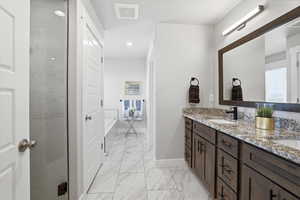 Full bathroom featuring double vanity, light marble finish floors, a shower stall, and recessed lighting