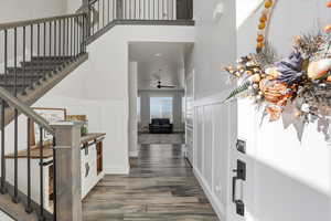 Foyer entrance featuring a decorative wall, wainscoting, stairs, wood finished floors, and a high ceiling