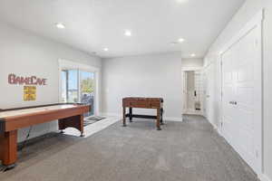 Recreation room with light colored carpet and recessed lighting