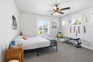Carpeted bedroom featuring a ceiling fan and baseboards