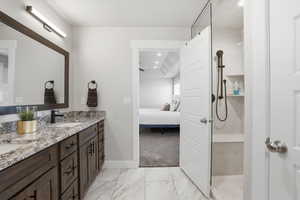 Bathroom with double vanity, walk in shower, connected bathroom, light marble finish flooring, and recessed lighting