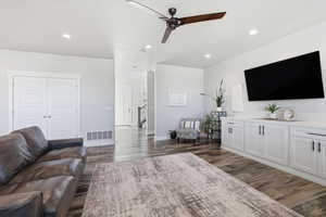 Living room featuring recessed lighting, dark wood-style flooring, and a ceiling fan