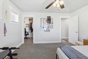 Bedroom with a spacious closet, light carpet, and ceiling fan