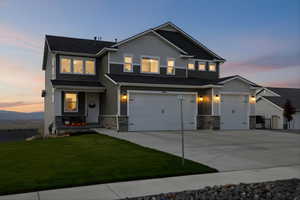 Craftsman house with stone siding, board and batten siding, driveway, a lawn, and a garage