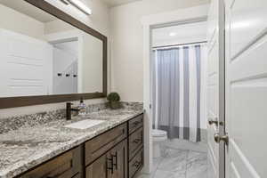Full bath with vanity, light marble finish floors, and shower / bathtub combination with curtain