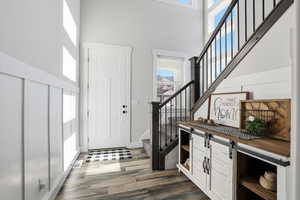 Foyer featuring plenty of natural light, stairs, dark wood-style flooring, and a high ceiling
