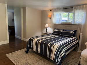 Bedroom featuring dark wood floors and baseboards