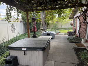 Fenced backyard with a patio area, a pergola, and a hot tub