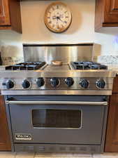 Kitchen view of brown cabinetry, designer Viking range, and light stone countertops