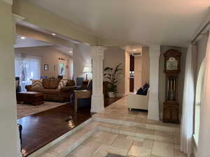 Living area with decorative columns, stone tile floors, and recessed lighting