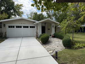 View of front of property featuring a front lawn, driveway, and an attached garage