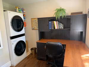 Office with dark wood flooring, stacked washer and dryer, and can be used as bedroom.