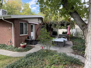 Exterior space featuring brick siding, a lighted patio with pergola area, and board and batten siding