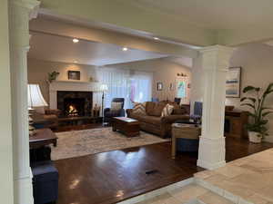 Living area with decorative columns, a premium fireplace, recessed lighting, and wood finished floors