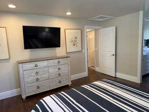 Bedroom with dark wood  floors, recessed lighting, ensuite bath, and attic access