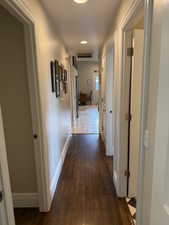 Hallway with dark wood flooring and baseboards