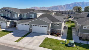 View of front of home featuring roof with shingles, driveway, stone siding, stucco siding, and a mountain view