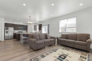 Living room with recessed lighting, light wood finished floors, and a chandelier