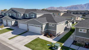 View of front facade featuring stone siding, concrete driveway, a residential view, stucco siding, and a shingled roof