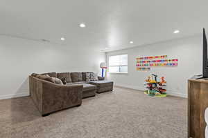 Carpeted living area featuring recessed lighting and a textured ceiling