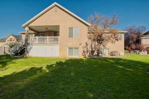 Back of house featuring stairs, a yard, and stucco siding