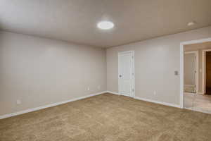Empty bedroom featuring light colored carpet and a textured ceiling