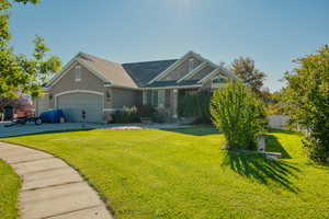 Craftsman-style home with a front lawn, stucco siding, an attached garage, and a shingled roof