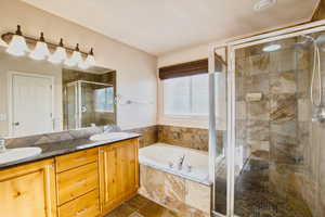 Primary Bathroom featuring double vanity, a garden tub, and a shower stall