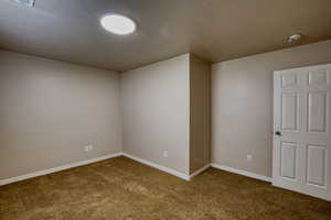 Empty bedroom featuring light colored carpet and a textured ceiling