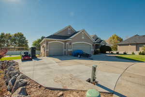 View of front of property featuring driveway, stucco siding, a garage, and stone siding