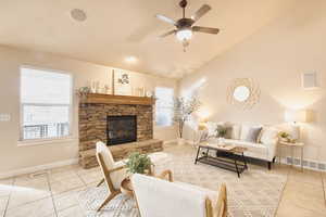 Living area with vaulted ceiling, light tile patterned flooring, a fireplace, and a ceiling fan